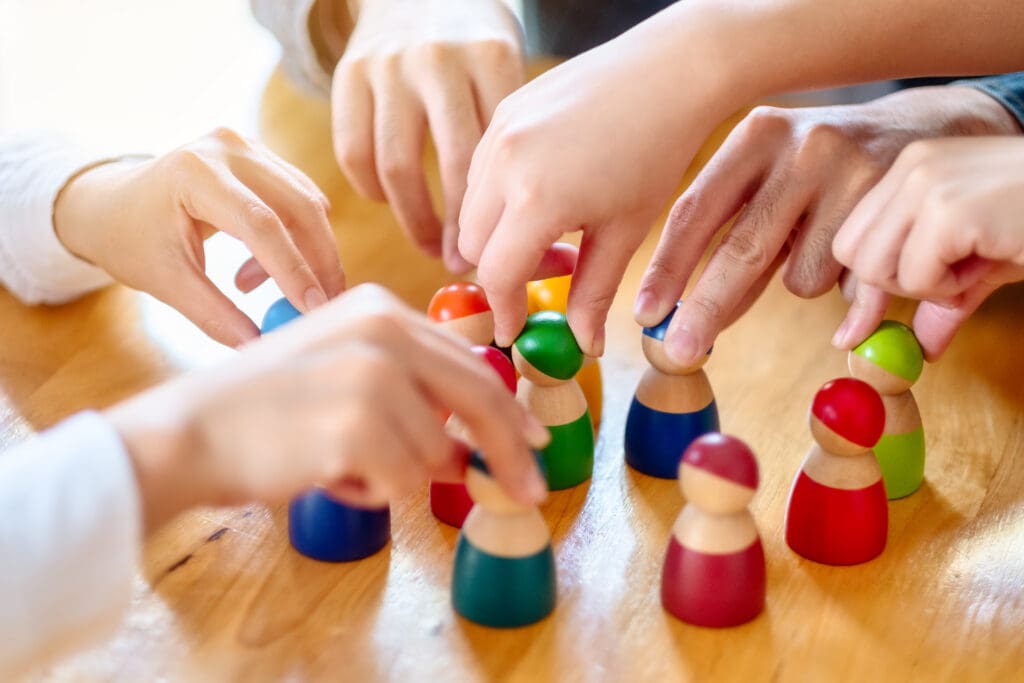 People choosing and picking up wooden figure from a group on the table